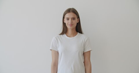Beautiful young smiling girl posing in front of camera in white blank t-shirt