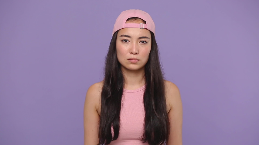Angry mad sad swearing young asian woman girl 20s years old in casual pink clothes cap posing scream shout isolated on pastel purple violet background studio. People sincere emotions lifestyle concept Royalty-Free Stock Footage #1056010817