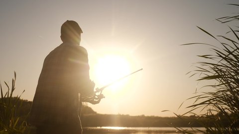 fisherman fishing fish silhouette on sunset. man recreation with fishing rod outdoor catching fish at sunrise. hobbies lifestyle fishing sport concept sunset. man relaxes with fishing rod