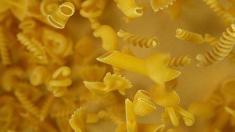 Super slow motion of flying uncooked italian pasta on golden background. Filmed on high speed cinema camera, 1000 fps.