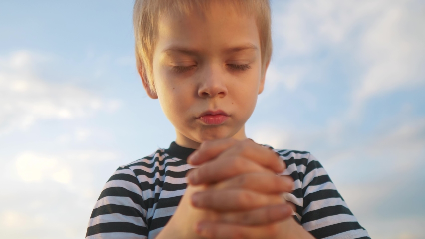 boy kid pray against a blue sky. child close-up concept faith religion and happy family. kid son jew crossed arms praying to god. kid catholic pray worship and gratitude and a happy childhood Royalty-Free Stock Footage #1056012713