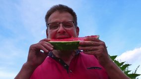 A man with glasses eats a red watermelon. Human hands. People. Food. Food intake. One man. Watermelon berry. Red watermelon. Vitamins Advertising video clip. Vegetarian food. Kitchen tool. Fruits.