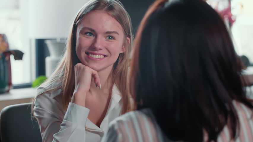 Beautiful smiling young 20-25 year old Caucasian blonde woman taking job interview at modern loft office meeting table. Royalty-Free Stock Footage #1056016112