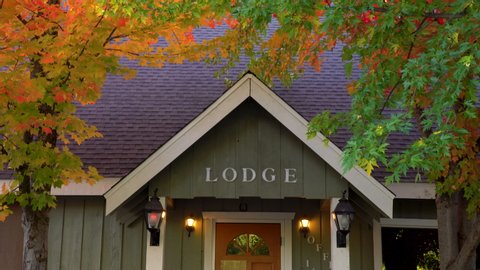 Pan shot of cozy lodge entrance situated in vibrant fall foliage in Mount Shasta, California