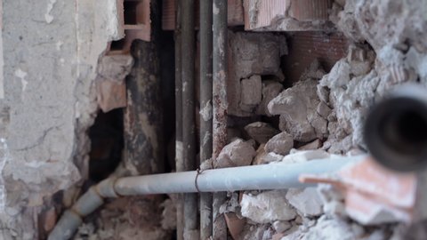 Installation of copper pipelines inside the concrete wall on construction site. Cracked and damaged old building brick wall with rusty unfunctioned tubes. Repair works with water or gas pipes in the