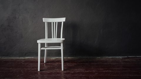 The white chair stands in an empty room with brown floors and gray walls