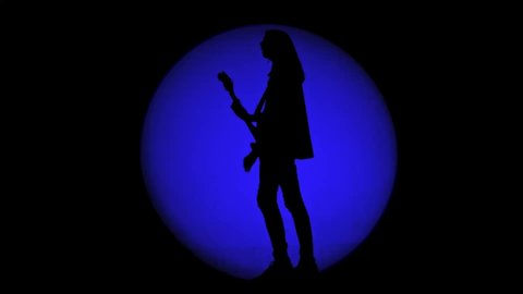 Shadow of an unrecognizable guitarist in a round beam of blue light. Musician playing a lead guitar and singing a song. Cloud of smoke is coming from the left