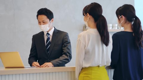 Young asian receptionist talking with customers with surgical mask. Hotel worker. Store clerk.