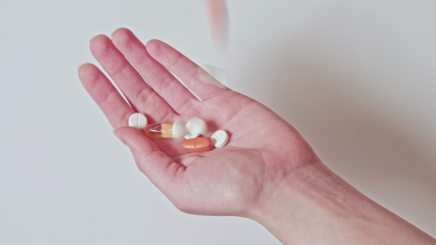 Medication overdose. Pharmaceutical drugs. Colorful pills scattering in hand isolated on neutral background. | Shutterstock HD Video #1056031280