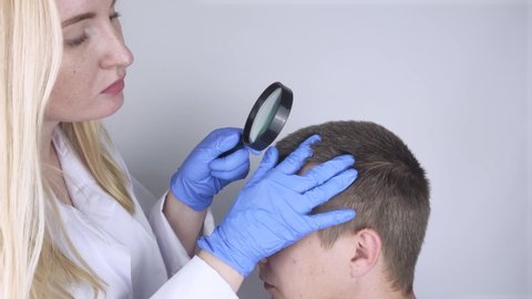 A trichologist examines the hair of a man who begins alopecia. Consultation with a dermatologist. Hair loss, alopecia, pruritus, burning head or seborrhea