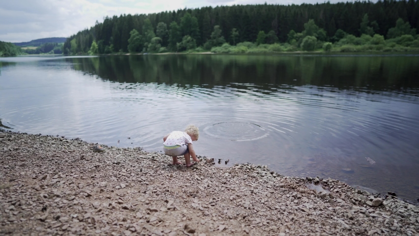 Baby girl throwing stone into water
