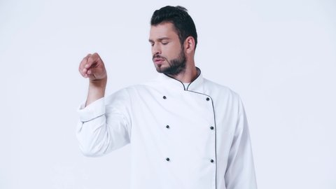 chef in uniform sprinkling salt isolated on white