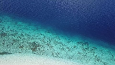 A drone shot a crystal clear sea water near the coast of Maumere, Flores, Indonesia. The turquoise water lets us see the coral reef. Deeper water is dark blue. Serenity and calmness. Hidden gem
