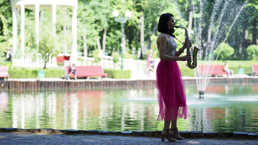 Musician is playing on the saxophone at the park