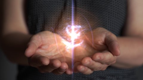 Woman creates and holds a clot of vital energy in her palms. Glowing lights in woman hands. Concept of sharing, giving, offering, taking care, protection. UHD, 4K