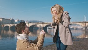 Happy woman taking a proposal about wedding and kissing her future husband. Handsome young man giving an engagement ring to her girlfriend. Couple dating on the bridge. Concept of love and marriage. - Powered by Shutterstock - Get 15% off with code: PIKWIZARD15