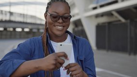 Stylish african american woman laughing, watching videos on smartphone, app