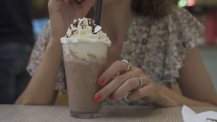 chocolate frappe or frapuccino with woman hand stirring iced. Close-up and selective focus. Royalty-Free Stock Footage #1056047549