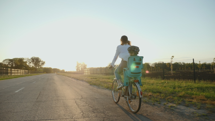 Happy mother with her smiling little son are riding a bike on the road at sunset, slow-motion Royalty-Free Stock Footage #1056048248