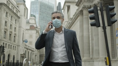 Corporate business man commuting to work wearing face mask in the city of London during Covid-19 Pandemic