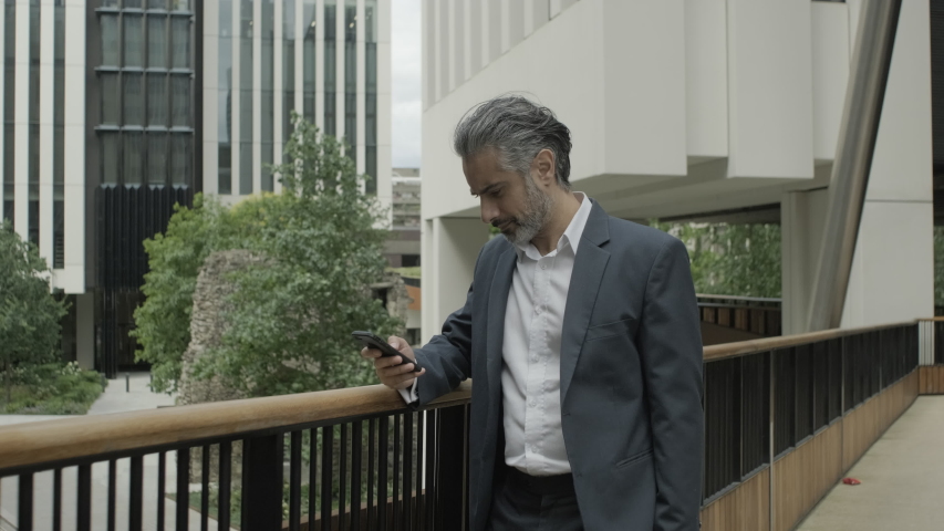 Mature adult business man on street talking on mobile phone in the city of London