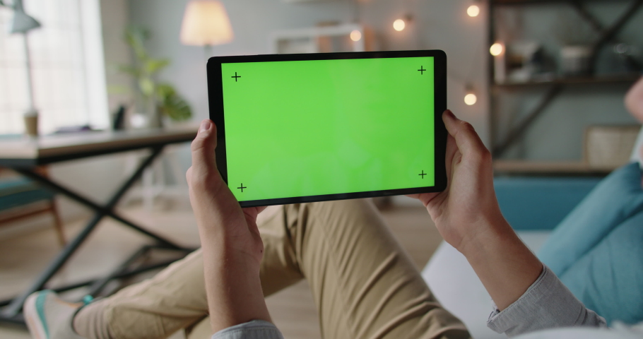 Caucasian guy having an online video conference, using tablet with mockup green screen, doing distant learning during self-isolation 4k footage Royalty-Free Stock Footage #1056048935