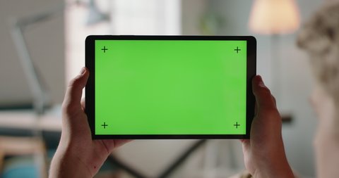 Close up shot of hands holding a tablet computer with green mock up screen. A template for video conference or online store 4k footage
