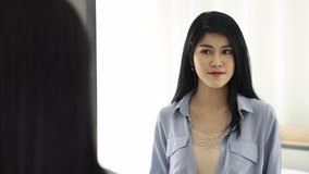 4K video of young and beautiful black long straight hair Asian woman tries to set her hairstyle to the best look. Reflection in mirror of pretty girl arranges self hair style with proud and happiness.