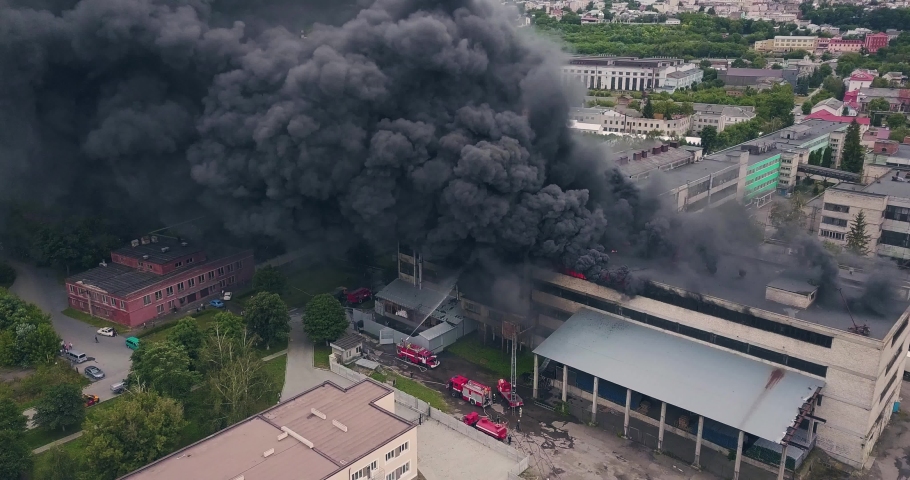 Aerial View of Firefigters Extinguishing a Large City Building Caught on Fire. Top View of a City District Covered in Dense Clouds of Black Rolling Smoke Rising from the Strongly Burning Old