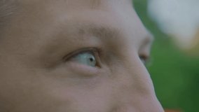 Close-up Portrait of a young man. Blue eyes of a young guy macro photography, natural beauty. The young guy looks away, blinks, dreams. Side view, in profile. Cold color, slow motion. 4K