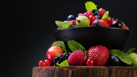 Mix of wild berries on black background, collection of strawberry, blueberry, raspberry and blackberry, 4K UHD video footage