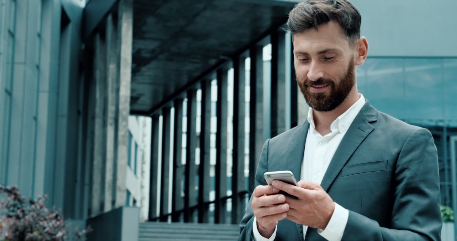 Successful Businessman texting Messages on his modern Smartphone.  Man  walking in Business District having online Communication in social Networks Royalty-Free Stock Footage #1056058490