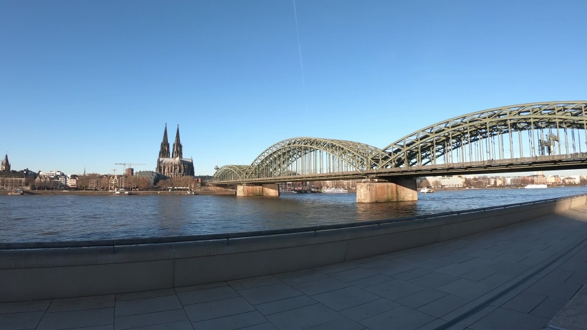 PAN SHOT - The Hohenzollern bridge over Rhine river on a sunny day. The Cologne Cathedral (Kolner Dom) in the city of Cologne, Germany. It is the largest Gothic church in northern Europe.