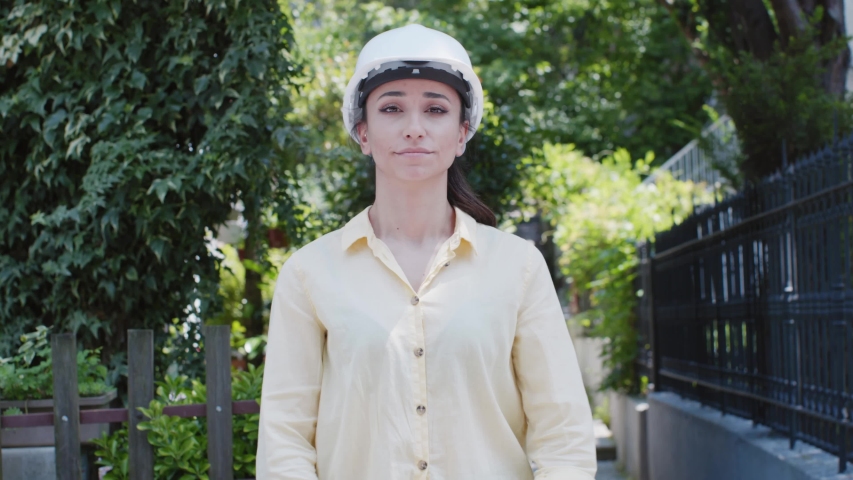 Portrait of female engineer smiling at camera with hard hat and protective vest. The woman