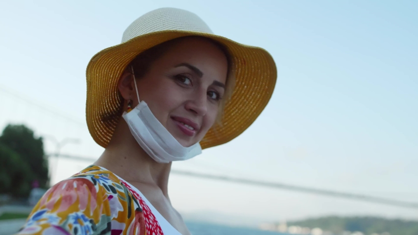 Attractive young beautiful woman on the Bosporus in Turkey poses for the camera. Woman in facial mask and gloves to prevent infection.