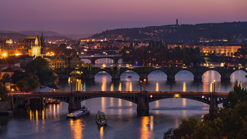 Prague, Czech Republic, dolly right timelapse sequence showing Prague cityscape with medieval bridges and boats on the Vltava river at dusk.  | Shutterstock HD Video #1056067931