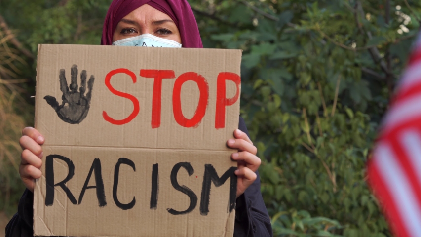 Stop racism slogan. Arab immigrant Muslim woman in a hijab supports the movement Black Lives Matter. Worldwide protests against institutionalized racism and police Royalty-Free Stock Footage #1056071828
