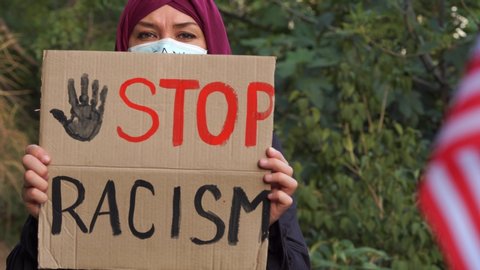 Stop racism slogan. Arab immigrant Muslim woman in a hijab supports the movement Black Lives Matter. Worldwide protests against institutionalized racism and police