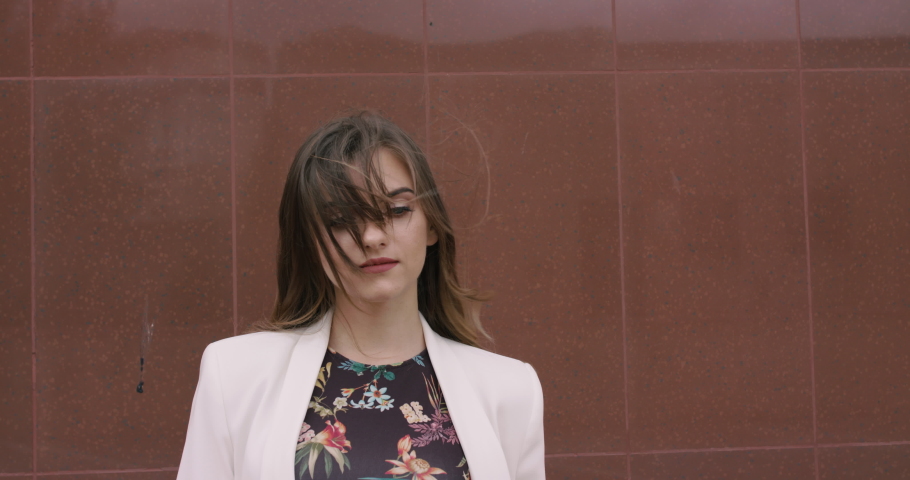 Portrait of thoughtful girl with strongly blowing hair outdoor on background. Slowly in 4K