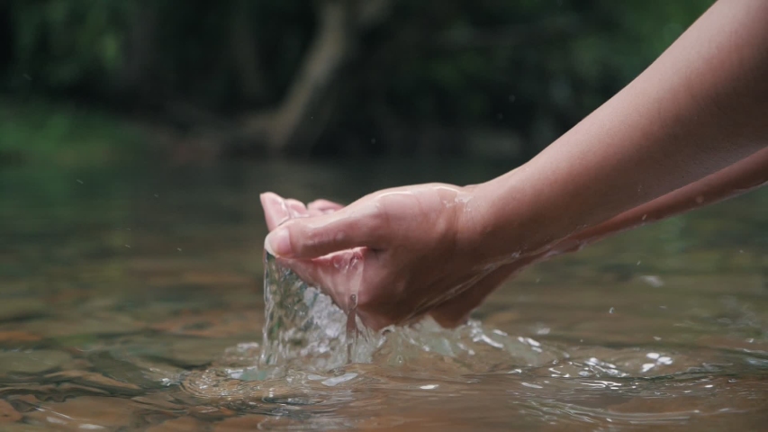 Hand scooping fresh stream water in the forest river or lake, Close up of holding pure stream water in cupped hand in Slow Motion. | Shutterstock HD Video #1056074873