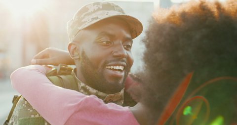 African American young handsome male soldier in uniform coming back home and meeting pretty happy girlfriend. Man in military clothes hugging and spinning beautiful girl outdoor. Close up.