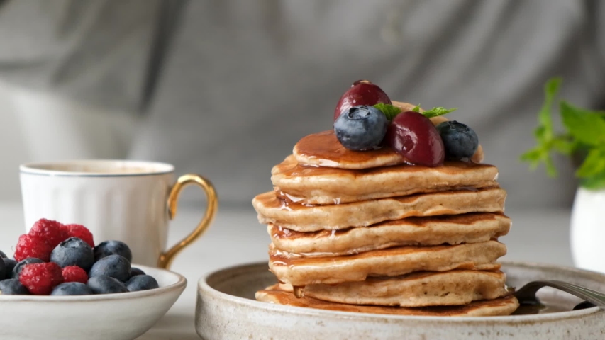 Pouring maple syrup on stack of oatmeal pancakes. Healthy vegan and vegetarian pancakes with berries and maple syrup. Slow motion Royalty-Free Stock Footage #1056084569