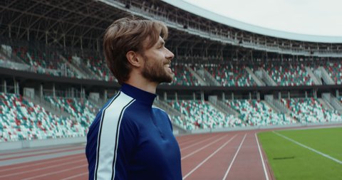Young adult Caucasian male sportsman soccer player entering and admiring a large empty stadium. Shot on RED Cinema camera