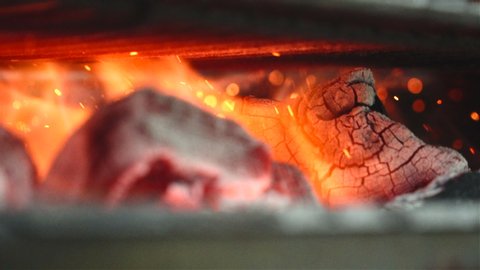 a close up of some very hot charcoal burning in a grill in slow motion and flames