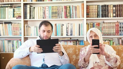 Arabic grandson and his grand mother surfing internet on their smart devices 