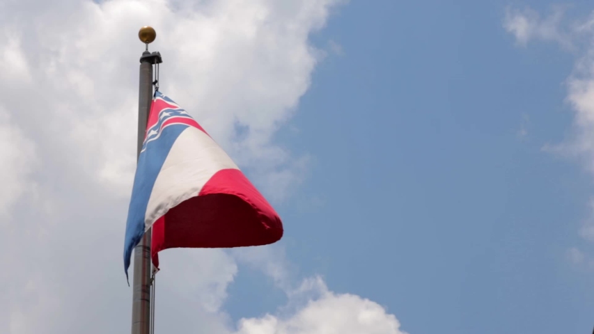 Mississippi State Flag waving in the wind against blue sky with clouds