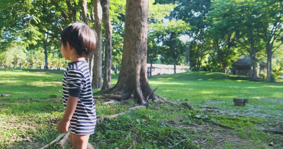 Adorable little boy playing with nature in city park morning sunrise