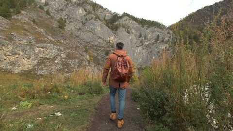 young hiker tourist traveler man with backpack traveling on mountain, Active lifestyle hiking male enjoying vacation travel tourism adventure summer landscape nature, back rear view. 4 K slow-mo