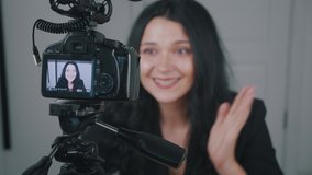 Business woman blogger recording video for internet vlog using professional camera. Female video vlogger talking to camera at home