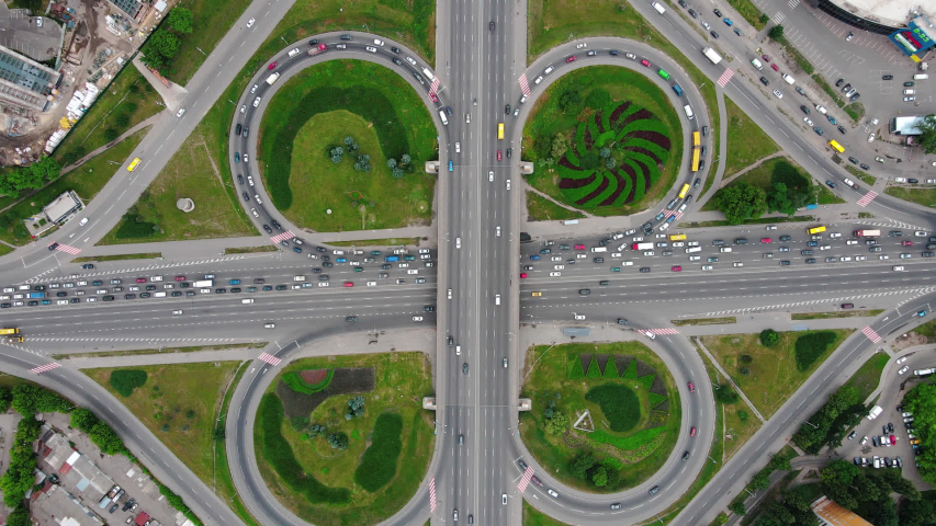 Overhead drone shot of traffic driving over roundabout with highway tunnel underneath, infrastructure and transportation in Kiev, Ukraine